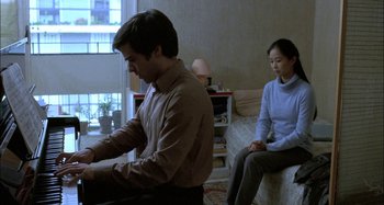 Movie still from “The Beat That My Heart Skipped” (2005), directed by Jacques Audiard – A man and a woman sitting on a couch; Medium shot, High angle