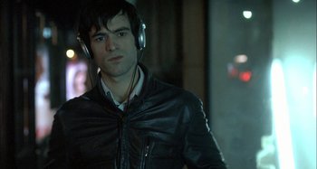 Movie still from “The Beat That My Heart Skipped” (2005), directed by Jacques Audiard – A man wearing a black leather jacket and headphones; Close Up shot, Over the shoulder angle