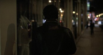 Movie still from “The Beat That My Heart Skipped” (2005), directed by Jacques Audiard – A person wearing a black leather jacket and headphones; Close Up shot, Over the shoulder angle