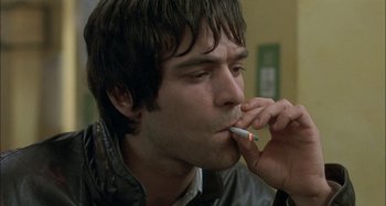 Movie still from “The Beat That My Heart Skipped” (2005), directed by Jacques Audiard – A man is smoking a cigarette in a room; Close Up shot, High angle