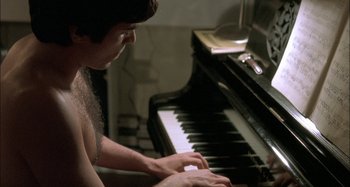 Movie still from “The Beat That My Heart Skipped” (2005), directed by Jacques Audiard – A man playing a piano in a room with a mirror; Medium shot, High angle