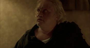 Movie still from “The Beat That My Heart Skipped” (2005), directed by Jacques Audiard – An old man with blonde hair and a black shirt; Close Up shot, Low angle