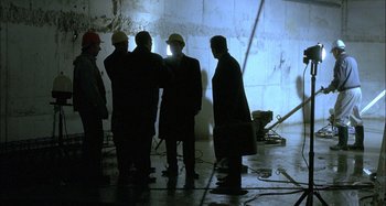 Movie still from “The Beat That My Heart Skipped” (2005), directed by Jacques Audiard – A group of men standing around in a room; Wide shot, High angle