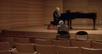 Movie still from “The Beat That My Heart Skipped” (2005), directed by Jacques Audiard – A person sitting at a piano in a room; Wide shot, High angle