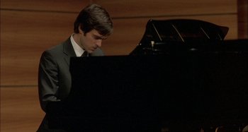 Movie still from “The Beat That My Heart Skipped” (2005), directed by Jacques Audiard – A man in a suit and tie playing a piano; Close Up shot, High angle