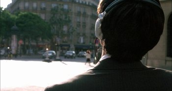 Movie still from “The Beat That My Heart Skipped” (2005), directed by Jacques Audiard – A man with headphones is standing on the street; Close Up shot, Over the shoulder angle