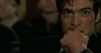 Movie still from “The Beat That My Heart Skipped” (2005), directed by Jacques Audiard – A person with a hand on his chin; Close Up shot, Over the shoulder angle
