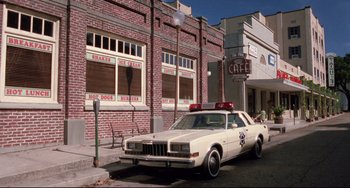 Movie still from “The Blob” (1988), directed by Chuck Russell – An old police car parked on the side of the street; Wide shot, Low angle