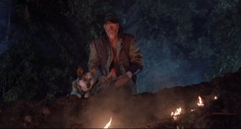 Movie still from “The Blob” (1988), directed by Chuck Russell – A man and a dog sitting in front of a fire; Wide shot, High angle