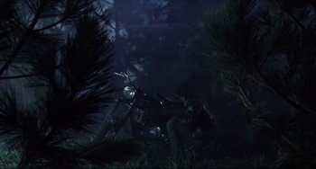 Movie still from “The Blob” (1988), directed by Chuck Russell – A man sitting on the back of a motorcycle in the woods; Wide shot, Low angle