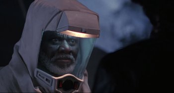 Movie still from “The Blob” (1988), directed by Chuck Russell – An older man wearing a helmet and a glass visor; Close Up shot, Over the shoulder angle