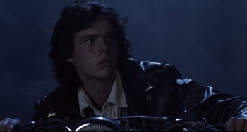 Movie still from “The Blob” (1988), directed by Chuck Russell – A man with long black hair sitting on top of a motorcycle; Close Up shot, Low angle