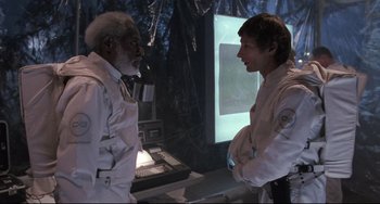 Movie still from “The Blob” (1988), directed by Chuck Russell – Two men are talking to each other in front of a computer screen; Medium shot, Over the shoulder angle