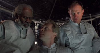 Movie still from “The Blob” (1988), directed by Chuck Russell – A man is getting his head shaved by two other men; Medium shot, Low angle