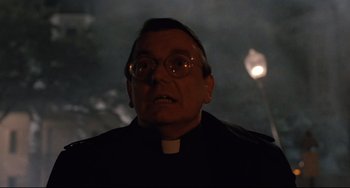 Movie still from “The Blob” (1988), directed by Chuck Russell – A man wearing glasses and a priest's outfit; Close Up shot, Low angle