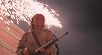 Movie still from “The Blob” (1988), directed by Chuck Russell – A person holding a guitar in front of fireworks; Medium shot, Low angle