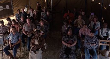 Movie still from “The Blob” (1988), directed by Chuck Russell – A large group of people sitting in front of a tent; Wide shot, High angle
