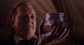 Movie still from “The Blob” (1988), directed by Chuck Russell – An older man holding a jar with something in it; Close Up shot, Low angle