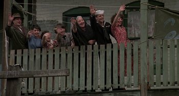 Movie still from “The Brink's Job” (1978), directed by William Friedkin – A group of people standing on top of a wooden fence; Wide shot, Low angle