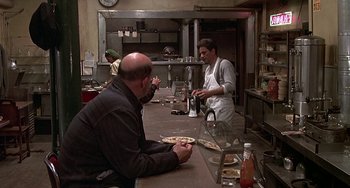 Movie still from “The Brink's Job” (1978), directed by William Friedkin – Two men sitting at a table in a kitchen; Wide shot, High angle