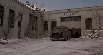 Movie still from “The Brink's Job” (1978), directed by William Friedkin – An old car parked in front of an old service station; Extreme Wide shot, High angle