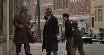 Movie still from “The Brink's Job” (1978), directed by William Friedkin – A group of people walking down a street; Wide shot, Over the shoulder angle