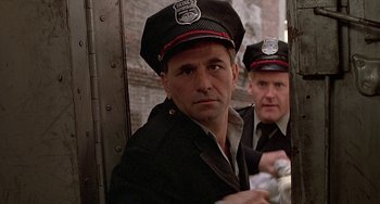 Movie still from “The Brink's Job” (1978), directed by William Friedkin – A man in a police uniform and a man in a red hat; Close Up shot, Low angle