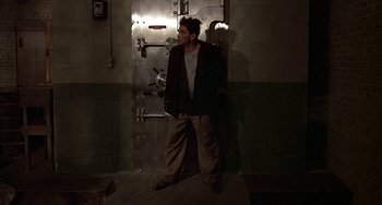 Movie still from “The Brink's Job” (1978), directed by William Friedkin – A man standing next to a door in a room; Wide shot, Low angle