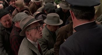 Movie still from “The Brink's Job” (1978), directed by William Friedkin – A group of men in hats and ties talking to each other; Medium shot, Over the shoulder angle