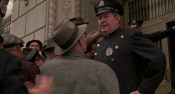 Movie still from “The Brink's Job” (1978), directed by William Friedkin – A man in a police uniform talking to another man in a hat; Medium shot, Over the shoulder angle