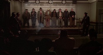 Movie still from “The Brink's Job” (1978), directed by William Friedkin – A group of men standing in front of a wall; Wide shot, High angle