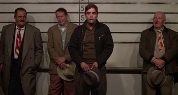 Movie still from “The Brink's Job” (1978), directed by William Friedkin – Two men standing next to each other in front of a wall; Medium shot, Low angle