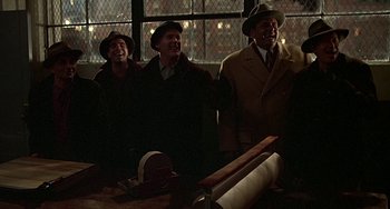 Movie still from “The Brink's Job” (1978), directed by William Friedkin – A group of men standing next to each other in a room; Medium shot, Low angle