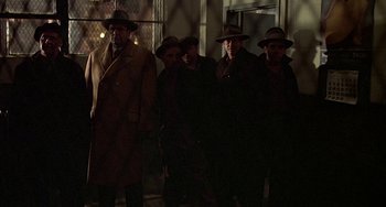 Movie still from “The Brink's Job” (1978), directed by William Friedkin – A group of men standing next to each other in a dark room; Wide shot, Low angle