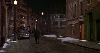 Movie still from “The Brink's Job” (1978), directed by William Friedkin – A man walking down a street at night; Extreme Wide shot, High angle
