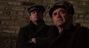 Movie still from “The Brink's Job” (1978), directed by William Friedkin – A couple of men standing next to a brick wall; Close Up shot, Low angle