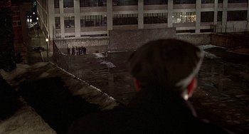 Movie still from “The Brink's Job” (1978), directed by William Friedkin – A group of people standing in front of a building at night; Extreme Wide shot, Over the shoulder angle
