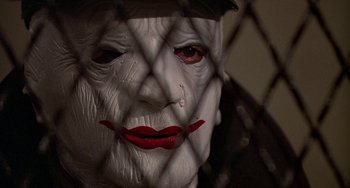 Movie still from “The Brink's Job” (1978), directed by William Friedkin – A person's face behind a chain link fence; Close Up shot, Low angle