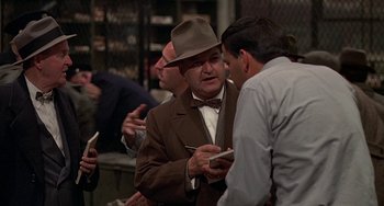 Movie still from “The Brink's Job” (1978), directed by William Friedkin – A group of men standing next to each other in a room; Medium shot, Over the shoulder angle