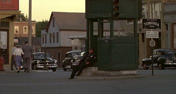 Movie still from “The Brink's Job” (1978), directed by William Friedkin – A man sitting on the side of the road next to a traffic light; Wide shot, High angle