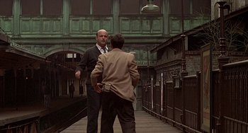 Movie still from “The Brink's Job” (1978), directed by William Friedkin – Two men in business suits are talking on a bridge; Wide shot, Low angle