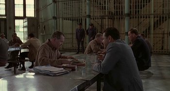 Movie still from “The Brink's Job” (1978), directed by William Friedkin – A group of men sitting at a table in a room; Wide shot, Over the shoulder angle