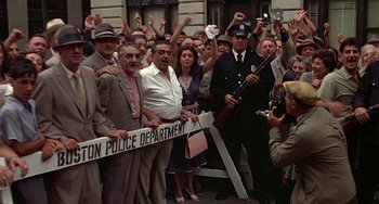 Movie still from “The Brink's Job” (1978), directed by William Friedkin – A group of people standing next to each other; Wide shot, High angle
