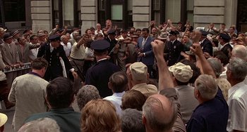 Movie still from “The Brink's Job” (1978), directed by William Friedkin – A crowd of people standing in front of a building; Wide shot, High angle