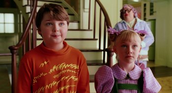 Movie still from “The Cat in the Hat” (2003), directed by Bo Welch – Two children and an older woman standing in front of a staircase; Medium shot, Over the shoulder angle
