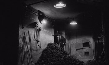 A man standing in front of a large pile of coal