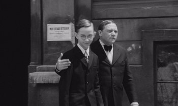 Two young men in suits and bow ties standing next to each other in front of a building