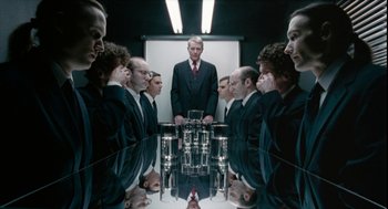 A group of men in suits are standing in front of a mirror