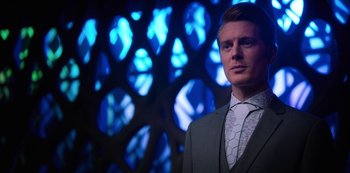 Movie still from “Altered Carbon” (2018), created by Laeta Kalogridis – A man wearing a suit and tie standing in front of a wall of lights; Close Up shot, Low angle