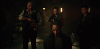 Movie still from “Altered Carbon” (2018), created by Laeta Kalogridis – A group of men standing in a dark room; Medium shot, Over the shoulder angle